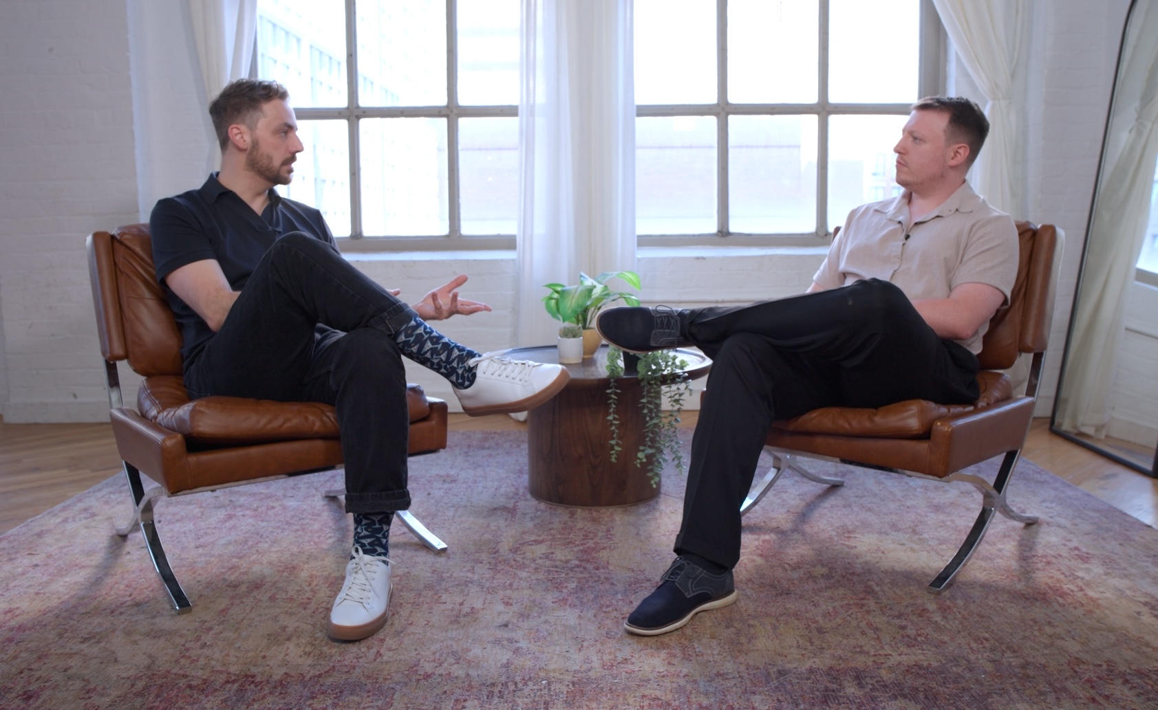 Jazek Creacy and Collin Watts seated across from each other in a sunlit New York loft, Jazek on the left and Collin on the right